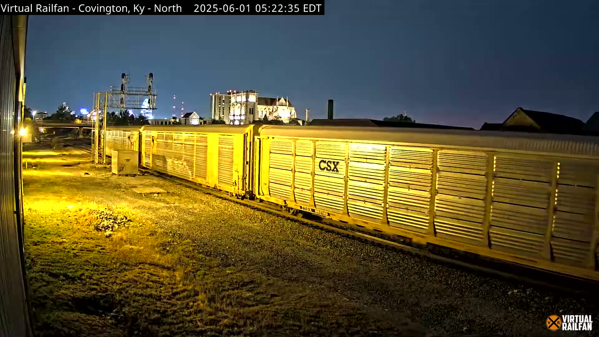 At night, a long yellow CSX freight train passes by under a dark, clear sky.