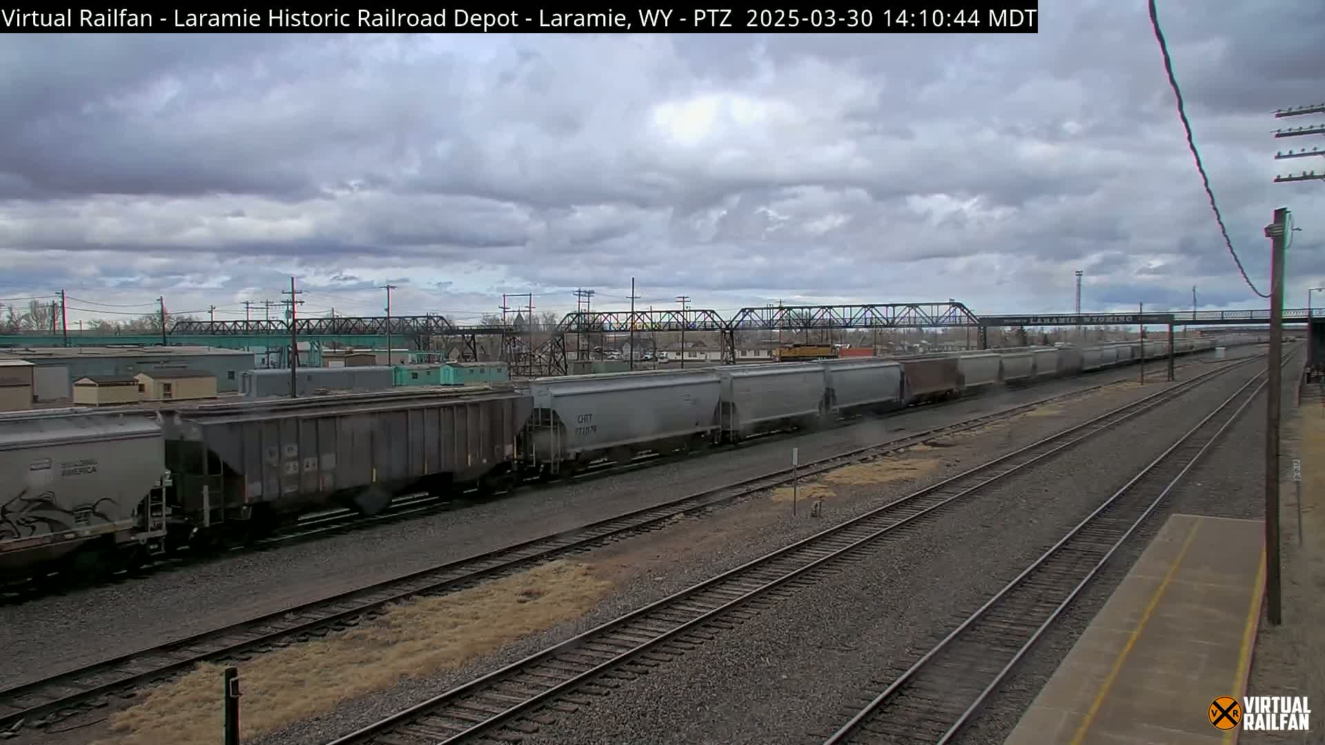 A long freight train sits on a railroad track under a cloudy sky.