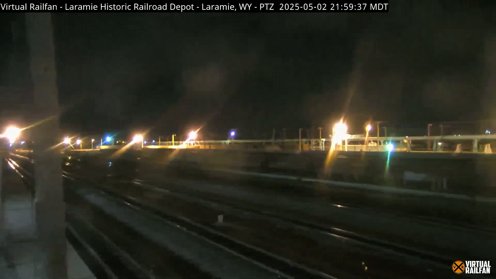 A nighttime view of a railroad yard with multiple sets of tracks illuminated by artificial lights.