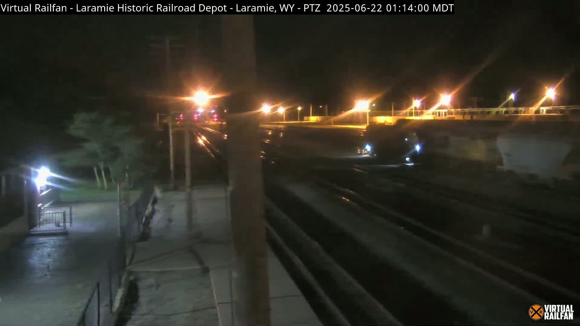 A nighttime view of a train passing through a railroad depot.
