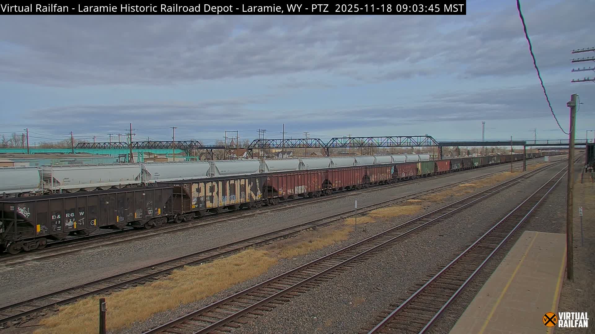 A nighttime view of railroad tracks and a depot, illuminated by streetlights, with clear skies.