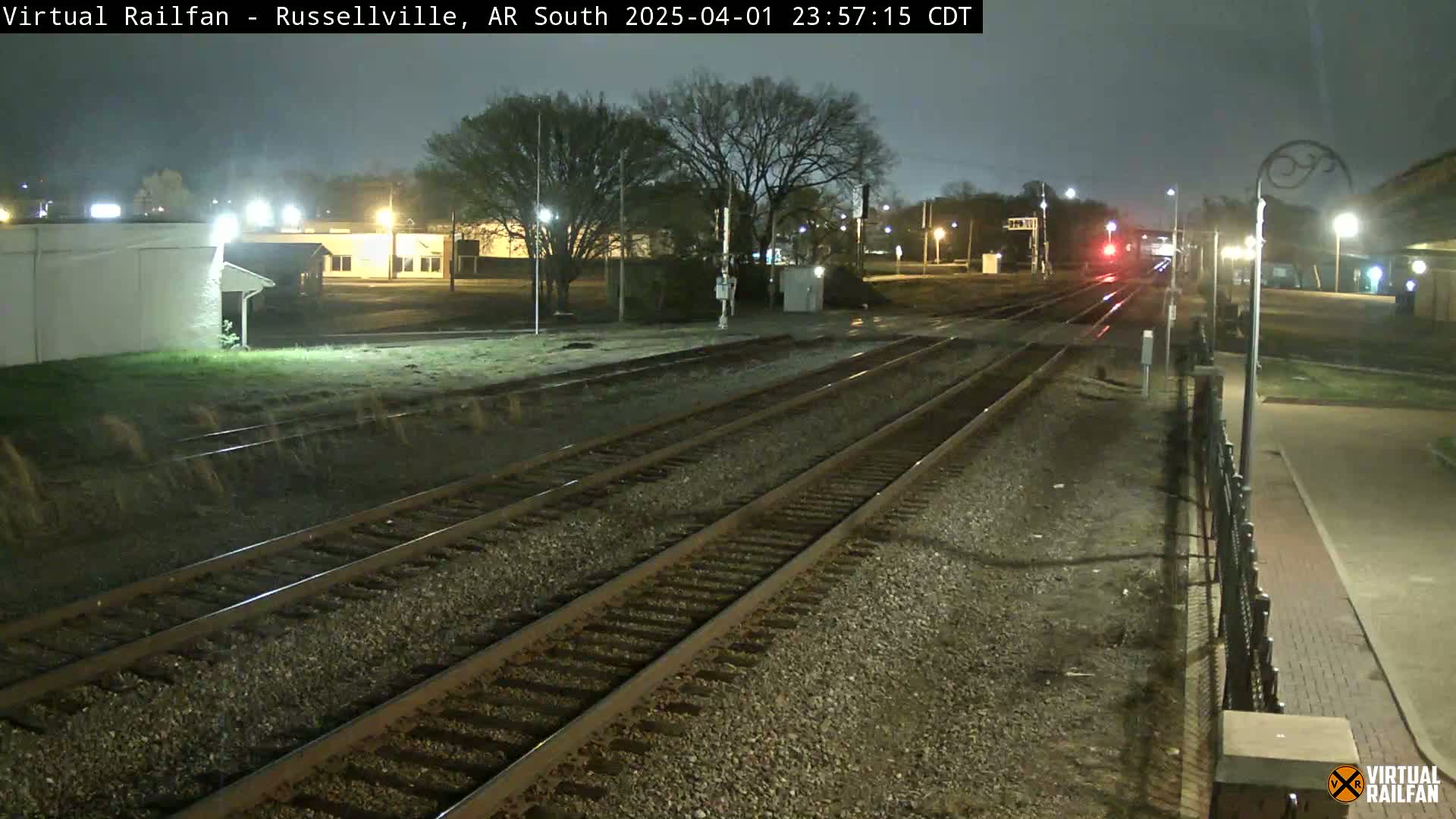 At night, a train passes by a railway station under a dark sky.