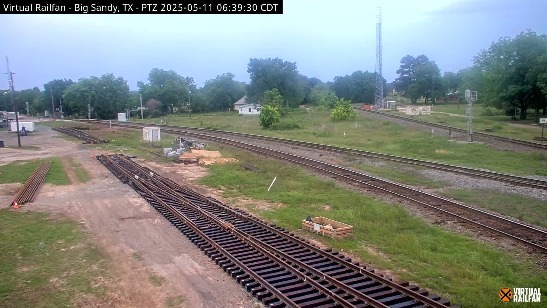 A railroad yard with several sets of tracks undergoing construction or maintenance under an overcast sky.