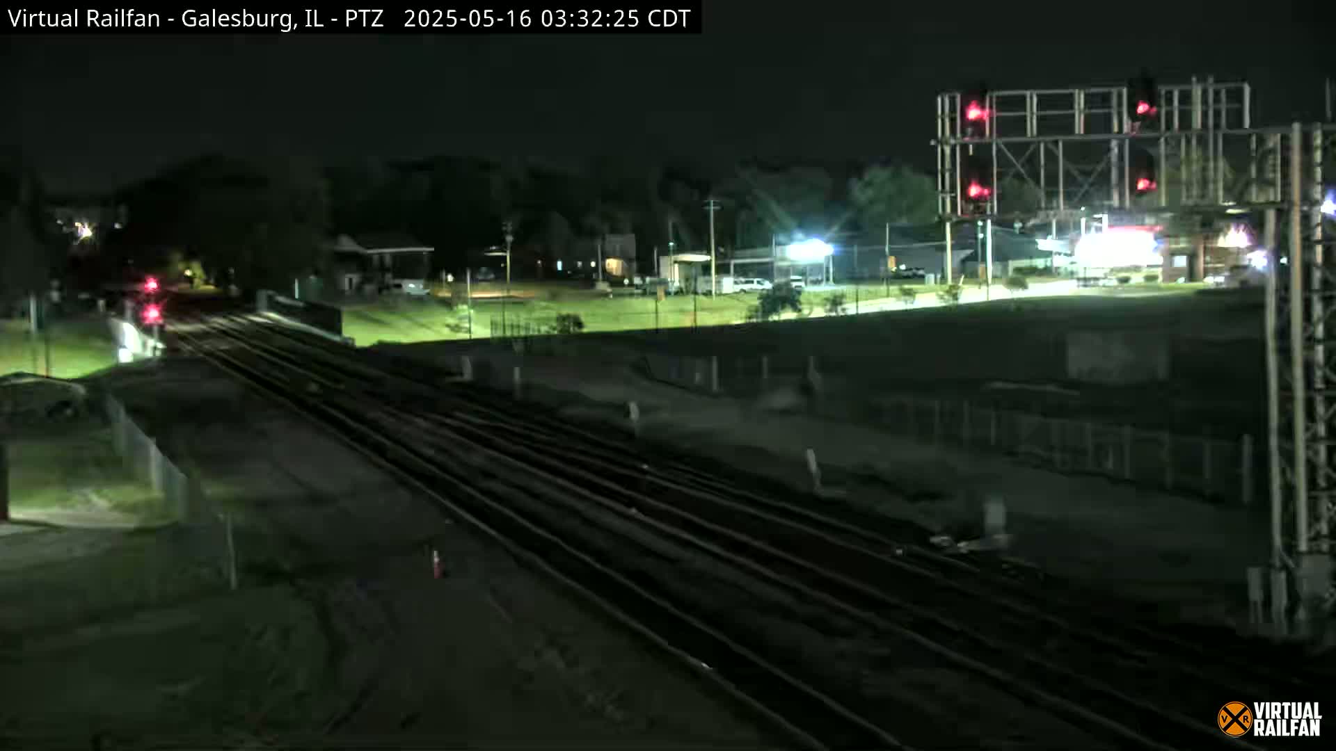 A nighttime view of railroad tracks, with a train in the distance, under clear skies.