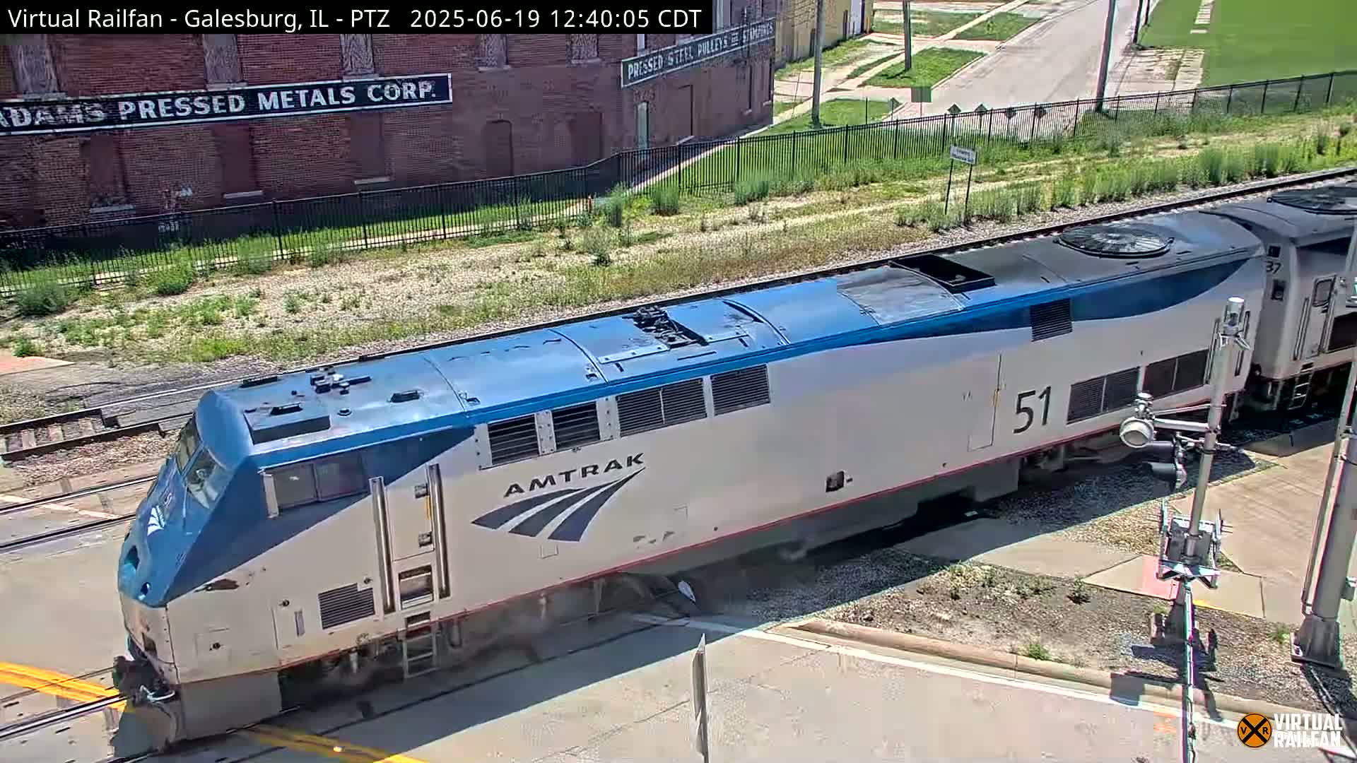 An Amtrak train, number 51, is crossing a road on a sunny day.