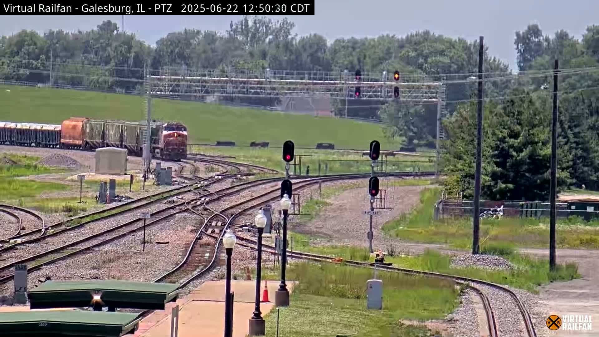 A freight train is passing through a railway yard on a sunny day.