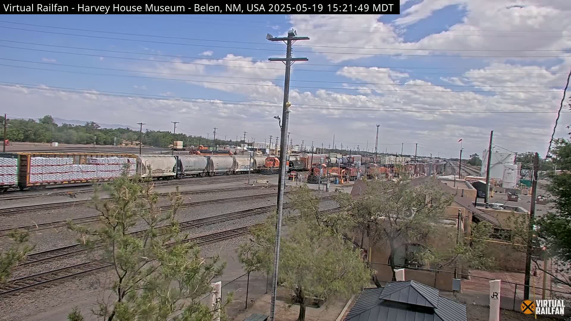 A long freight train sits on a railway under a partly cloudy sky.