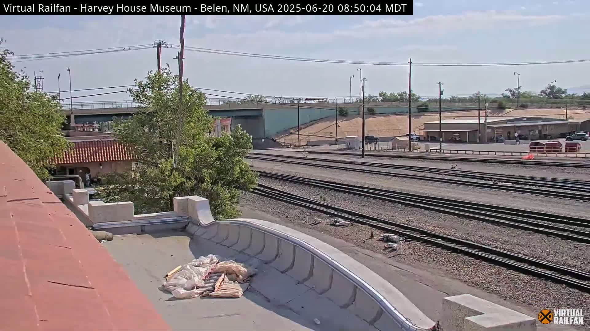 A view from a rooftop shows several sets of train tracks extending into the distance under a partly cloudy sky.
