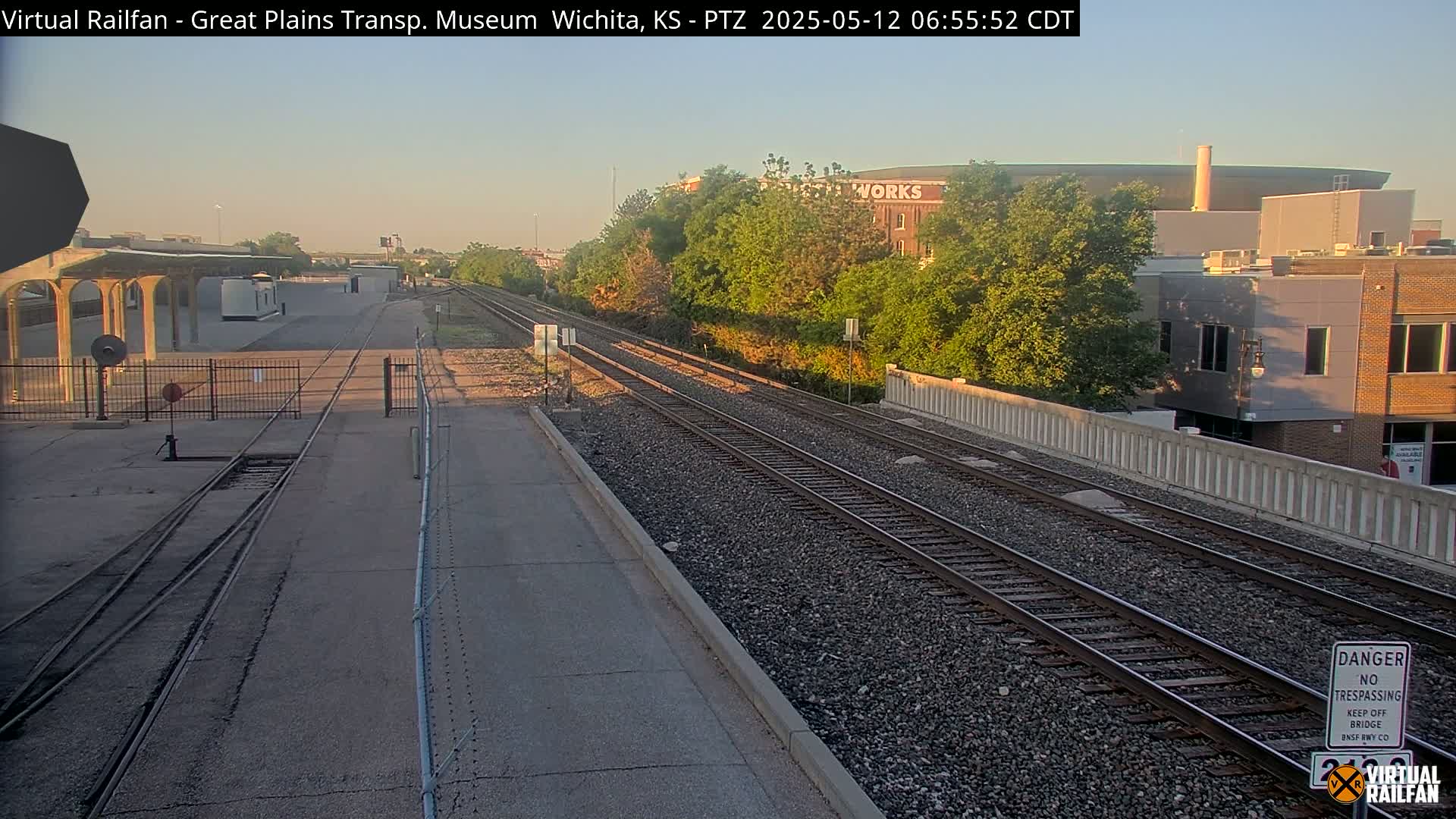 A view of train tracks leading toward a city under a clear, early morning sky.