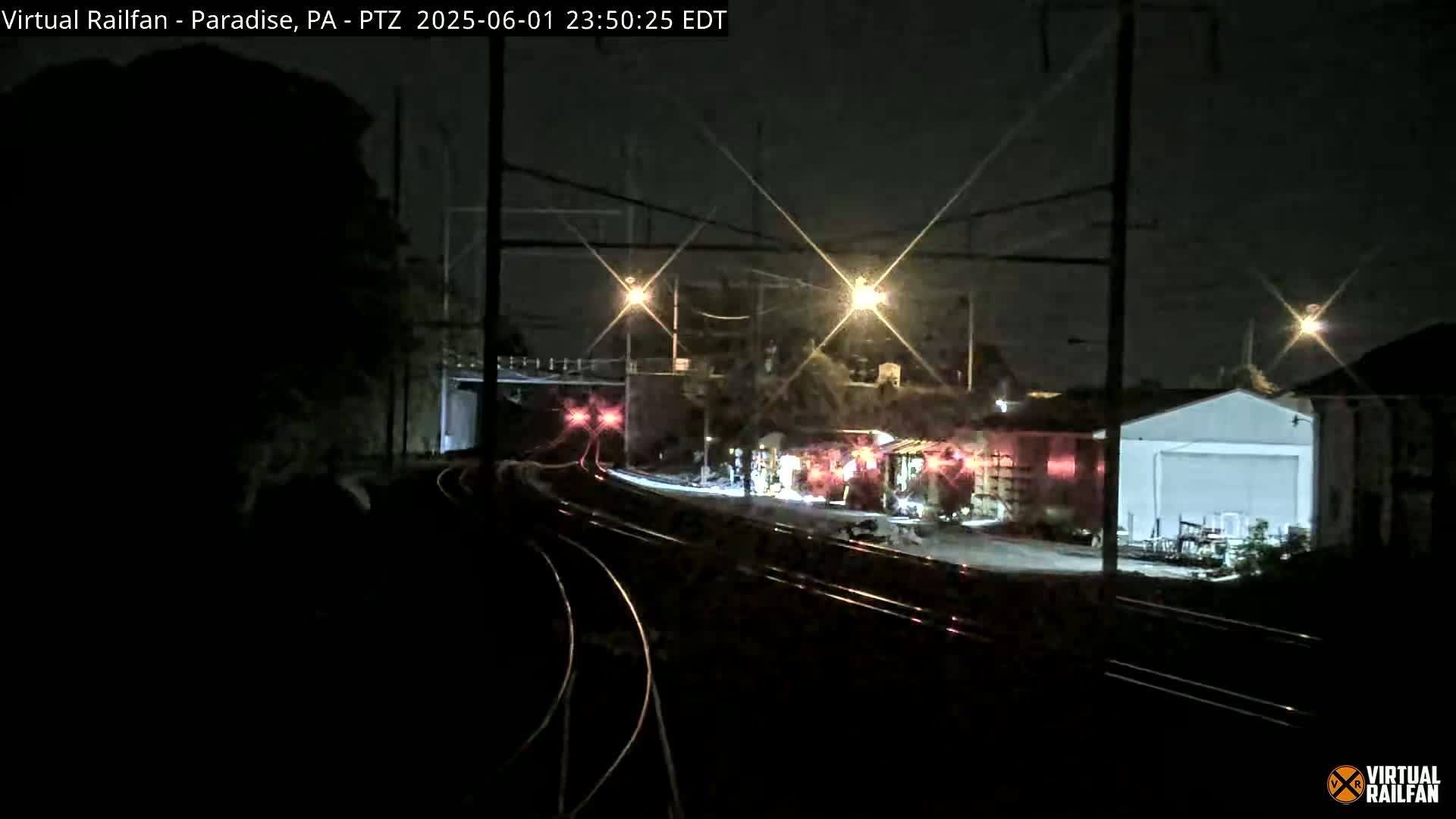 A nighttime view of railroad tracks and buildings illuminated by streetlights.