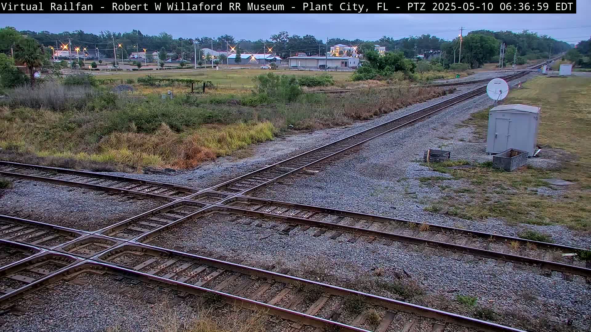 A railroad crossing intersects two sets of train tracks under a twilight sky.