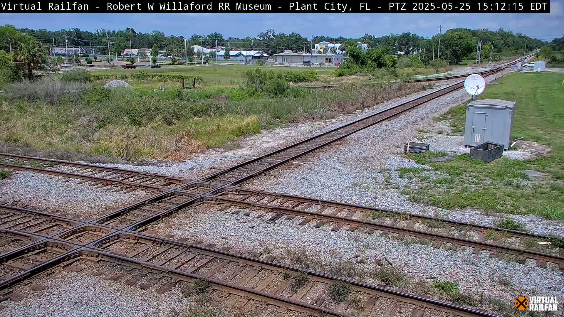 A railroad crossing with two sets of tracks intersects another set of tracks, under a partly cloudy sky.