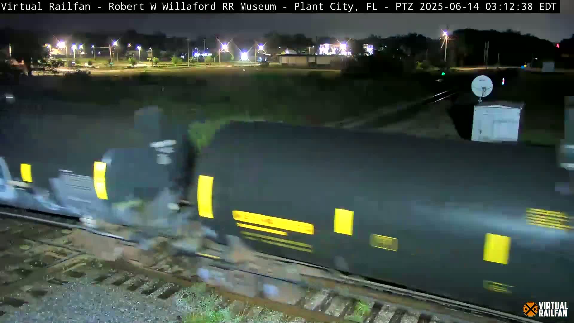 A long freight train moves along a track at night.