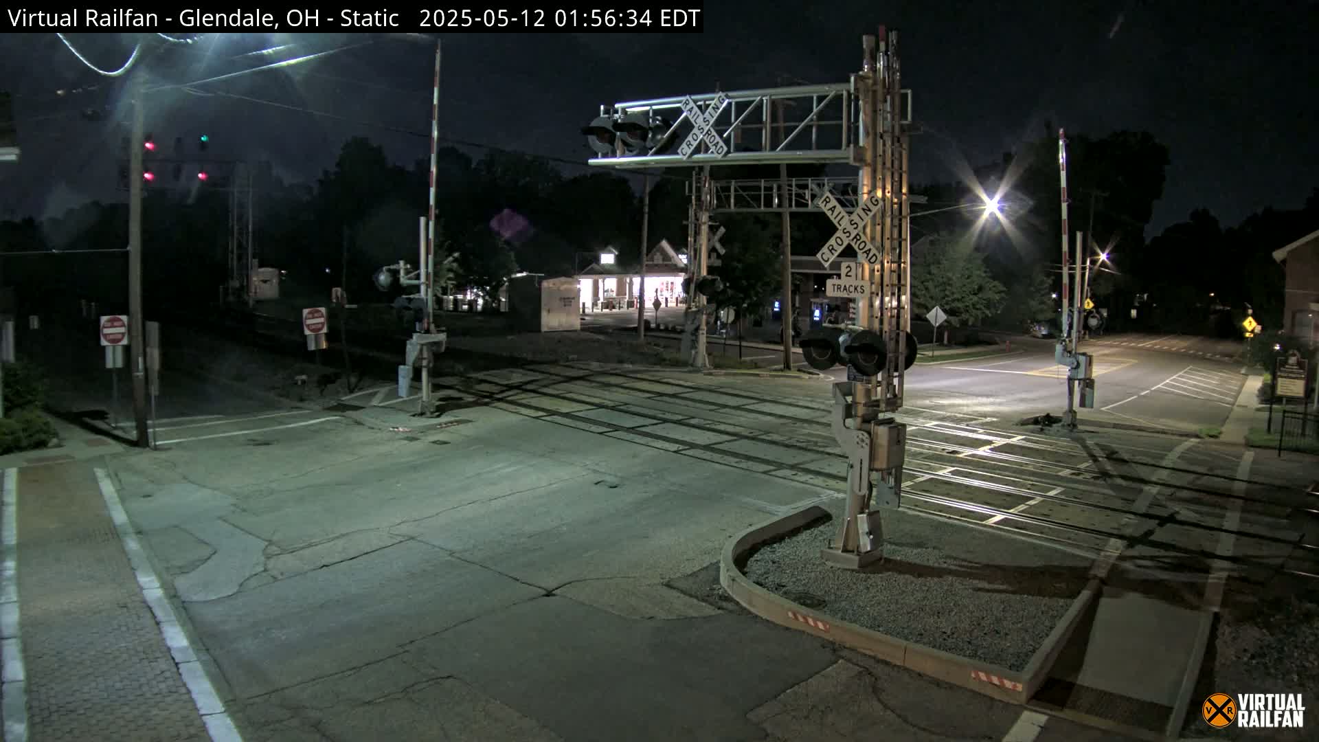 A nighttime view of a railroad crossing with lowered gates and illuminated signals.