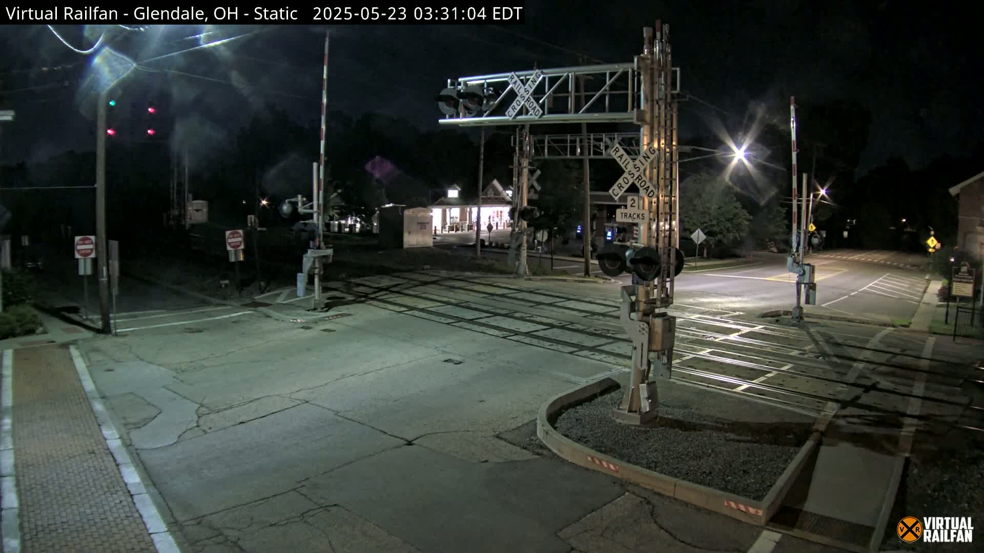 A nighttime view of a railroad crossing with lowered gates and flashing lights.
