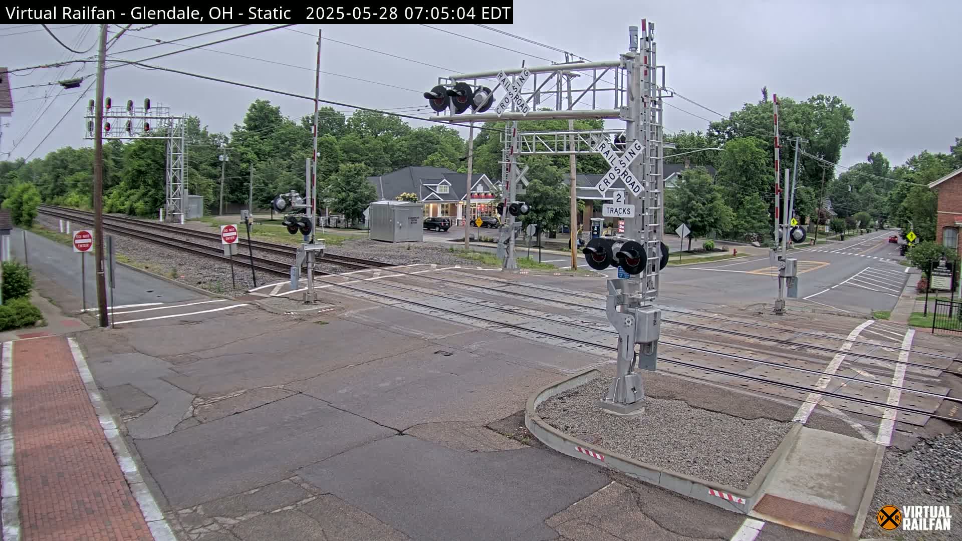A railroad crossing with lowered gates is shown on an overcast day.
