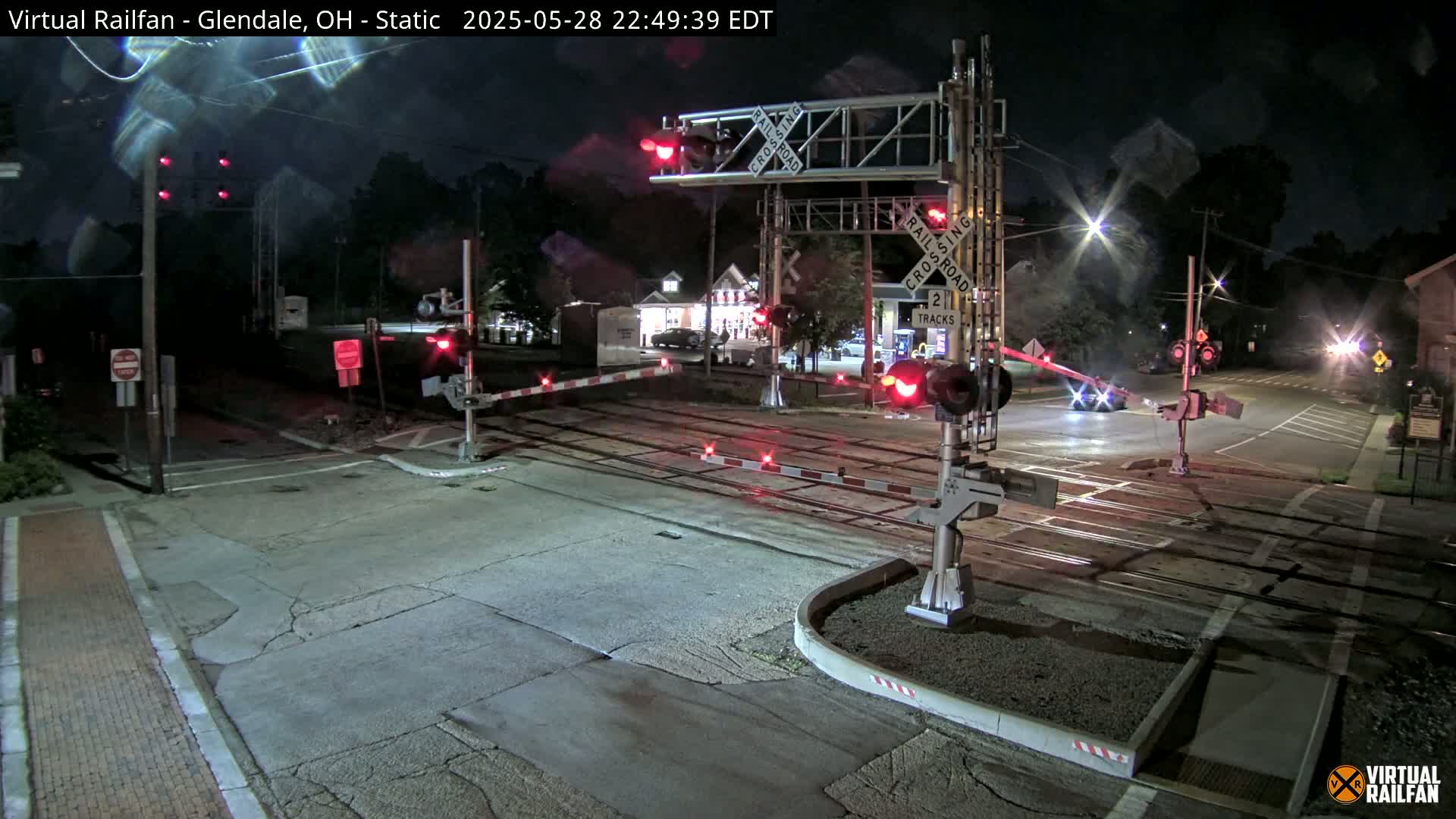 A nighttime view of a railroad crossing with its gates down and red lights flashing.