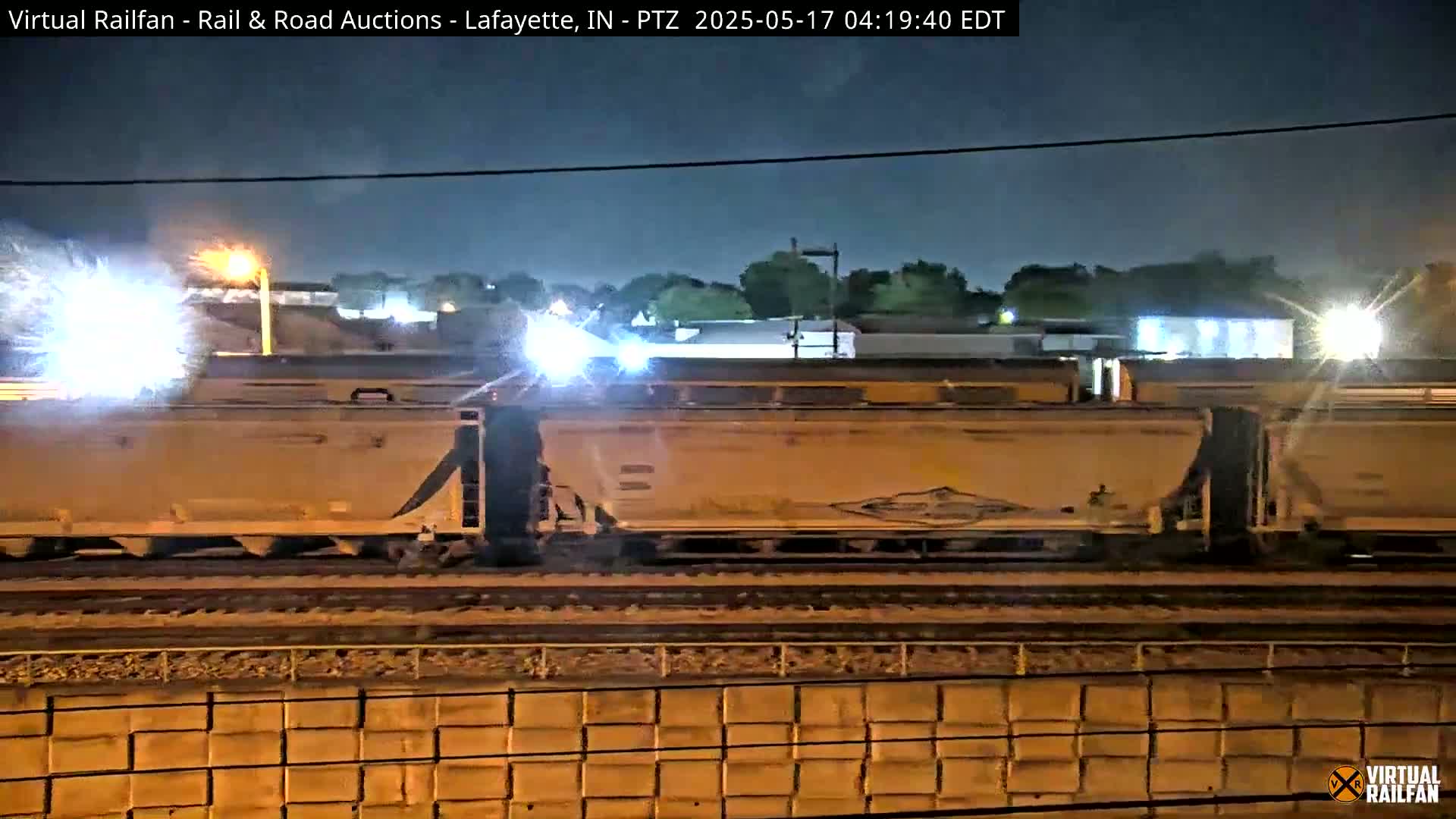 At night, a freight train passes by under bright lights.