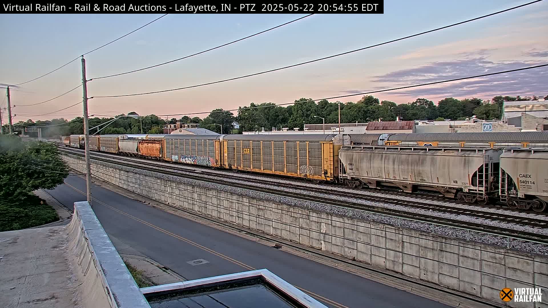 A long freight train passes by under a twilight sky.