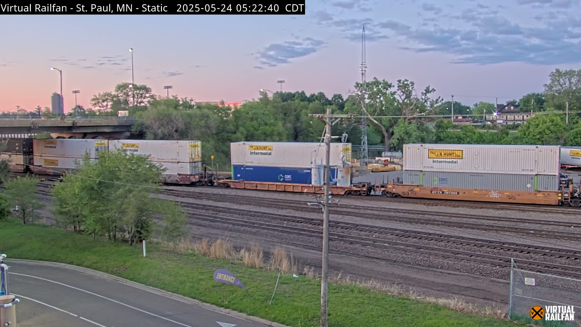 A train carrying several shipping containers sits on railway tracks under a twilight sky.
