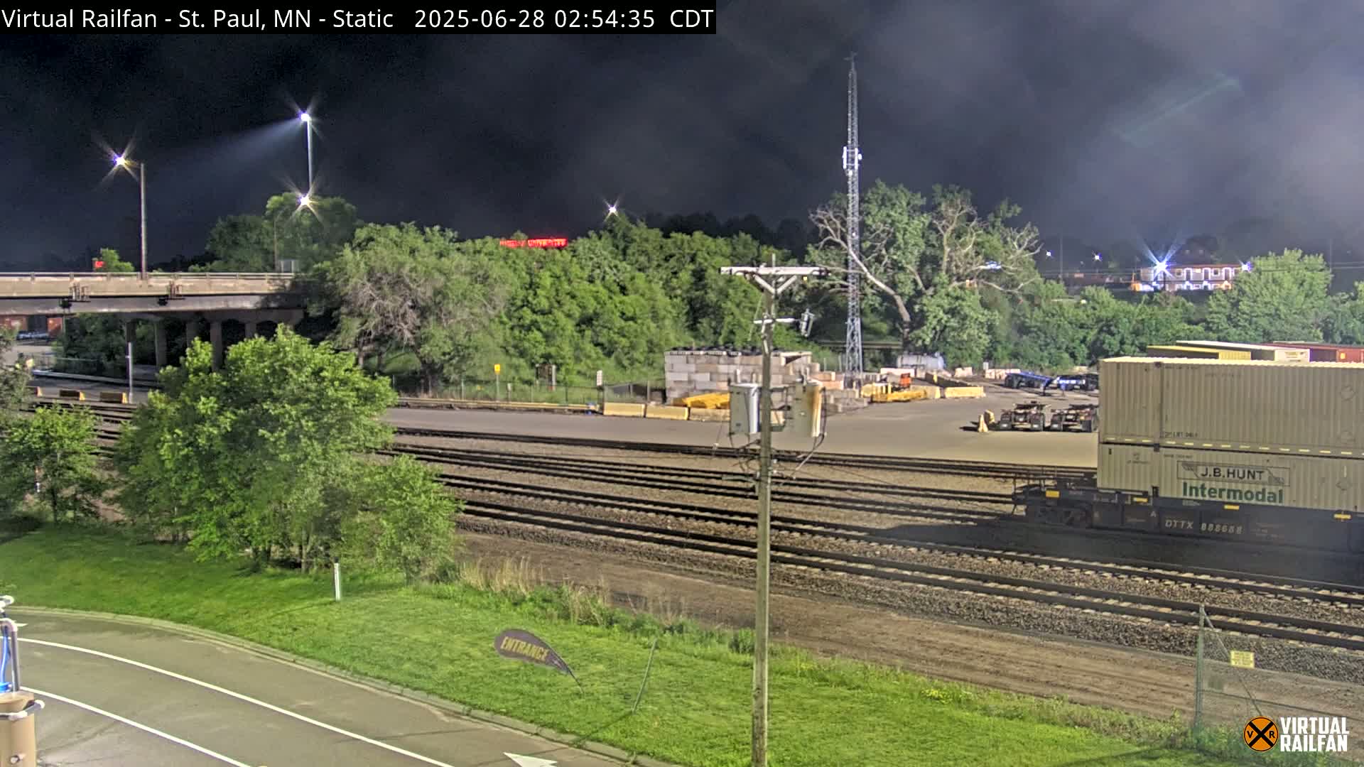 A nighttime view of railroad tracks and a train car under a dark, cloudy sky.