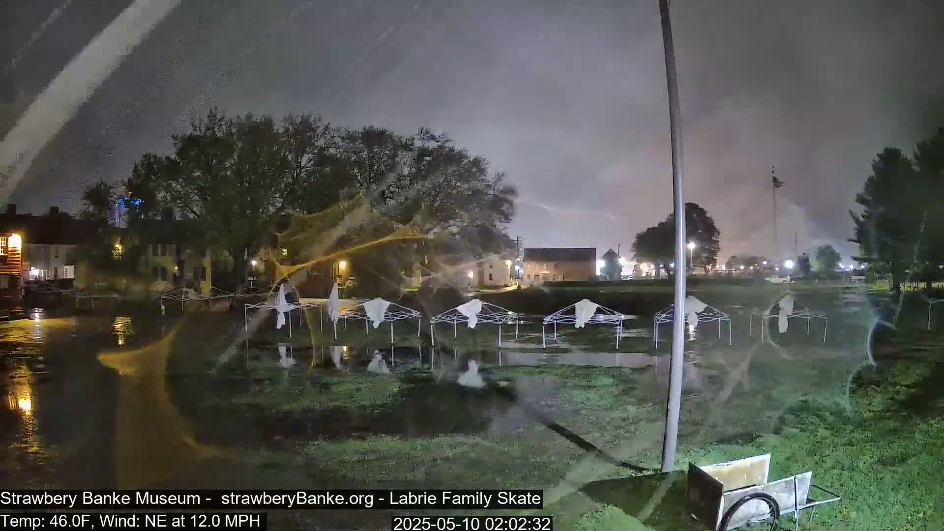 Several empty, overturned canopies sit in shallow floodwaters at night under a dark, stormy sky.