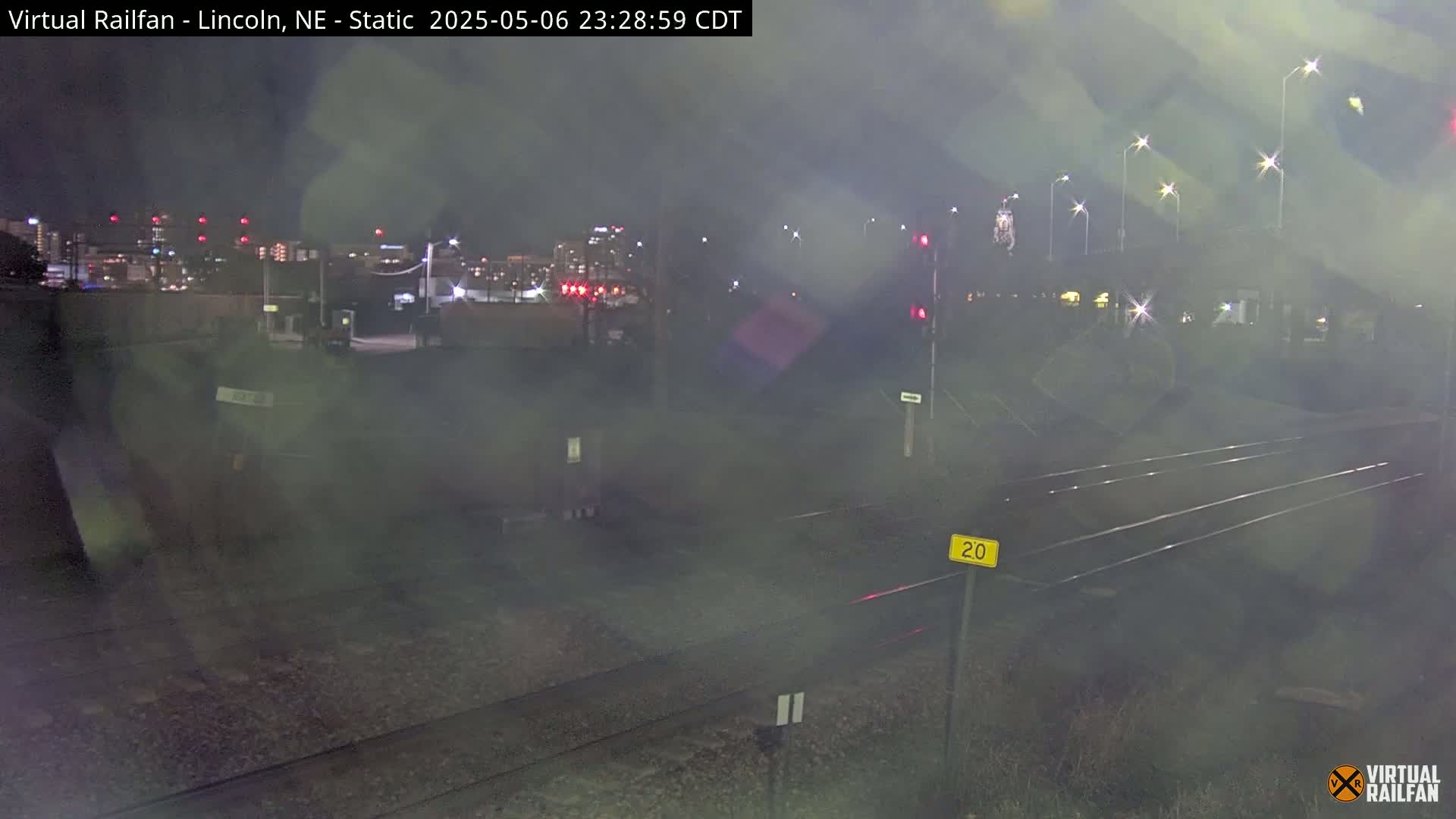 A nighttime view of train tracks and a city skyline in hazy conditions.