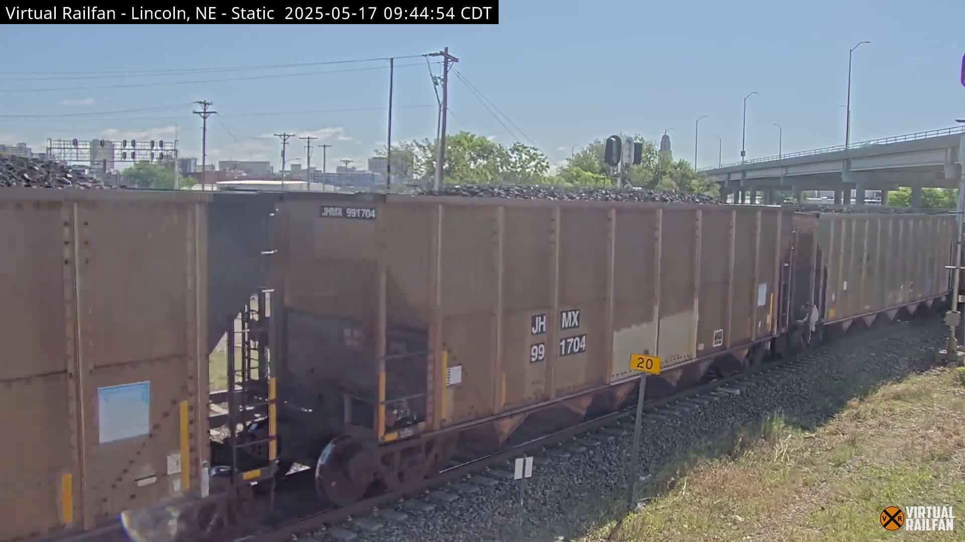 A long freight train carrying coal sits on railway tracks under a clear sky.