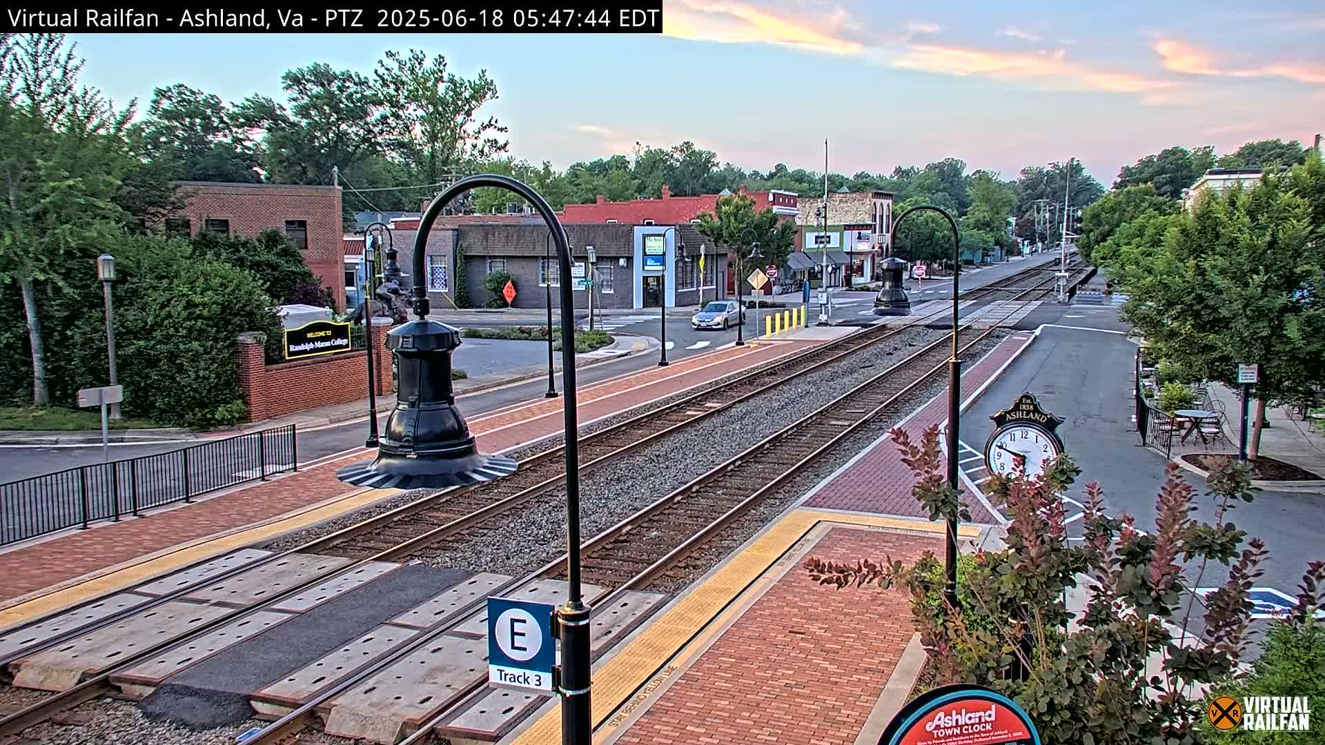 A train track runs through a town under a partly cloudy, twilight sky.