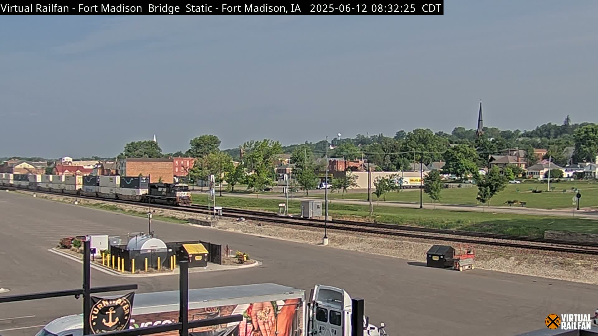 A long freight train passes by a town on a sunny day.