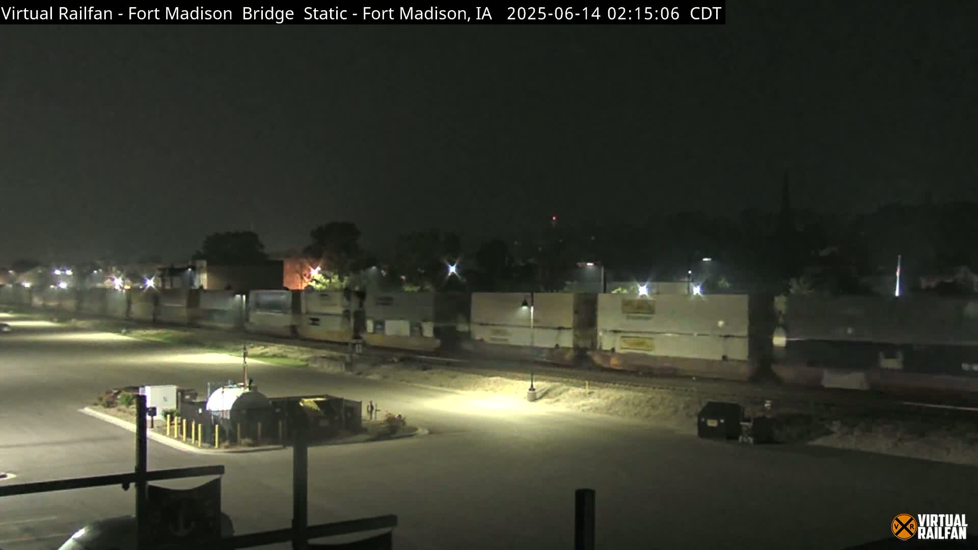 A long freight train passes through a dimly lit area at night.