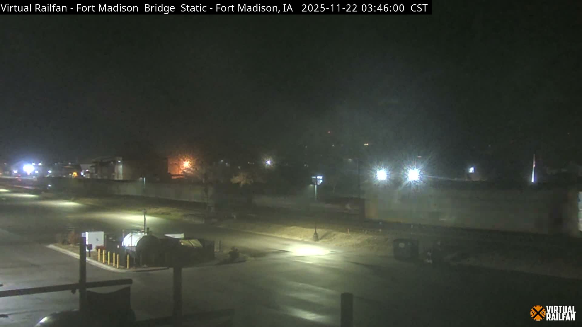 The image shows a clear night view of an outdoor urban or industrial area, illuminated by multiple streetlights and building lights, with roads and various structures visible under the dark sky.