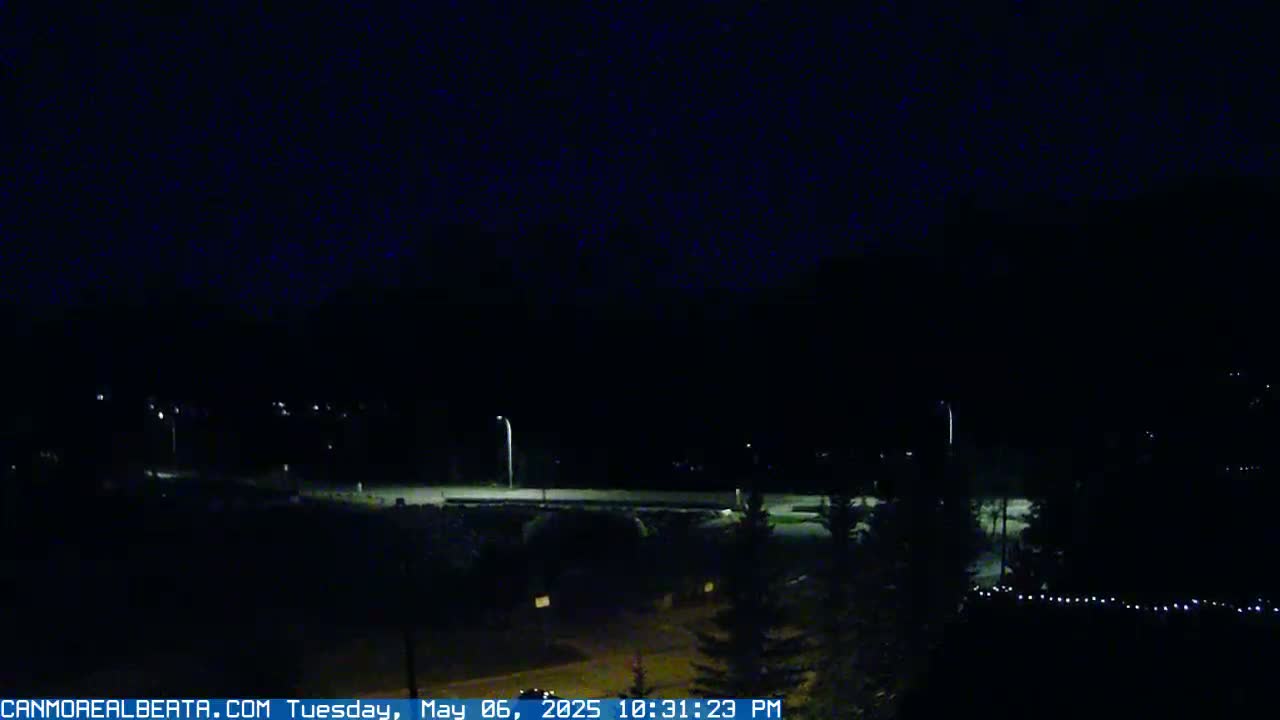 A nighttime view of a dimly lit road and surrounding area under a dark sky.