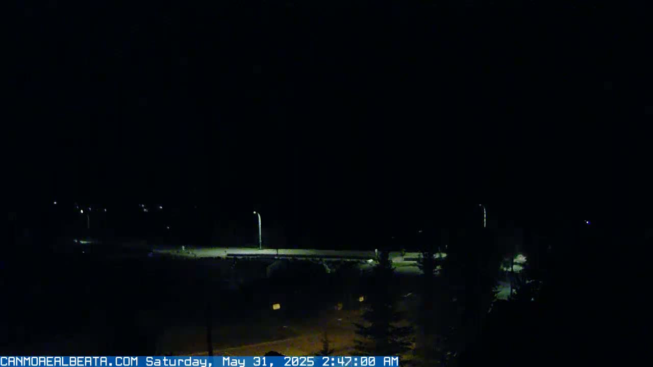A nighttime, low-light view of a road and sparsely lit surrounding area.