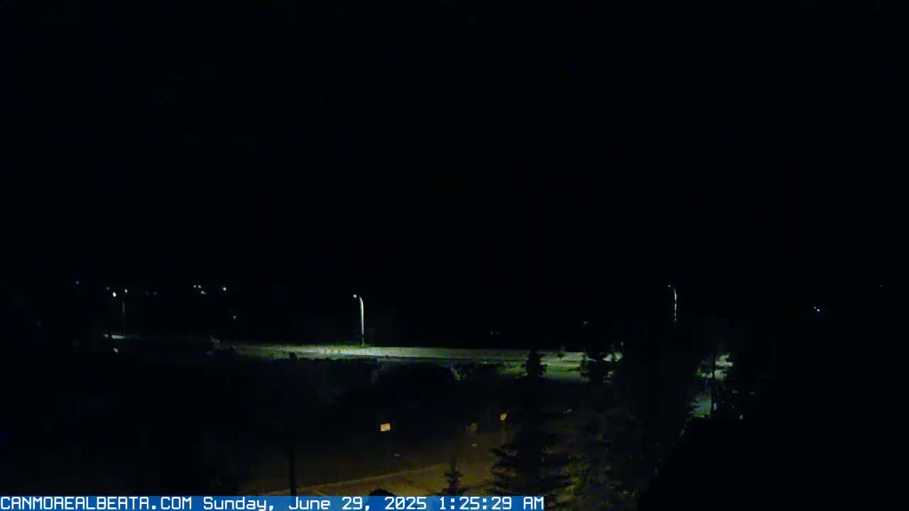 A nighttime view of a road and surrounding dark landscape under a clear, dark sky.