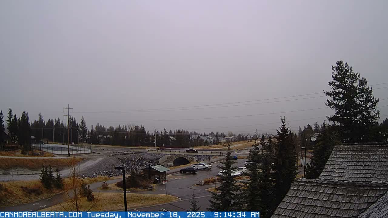 A partly cloudy day reveals a mountain range in the distance, with a parking lot, some construction, and a building in the foreground.