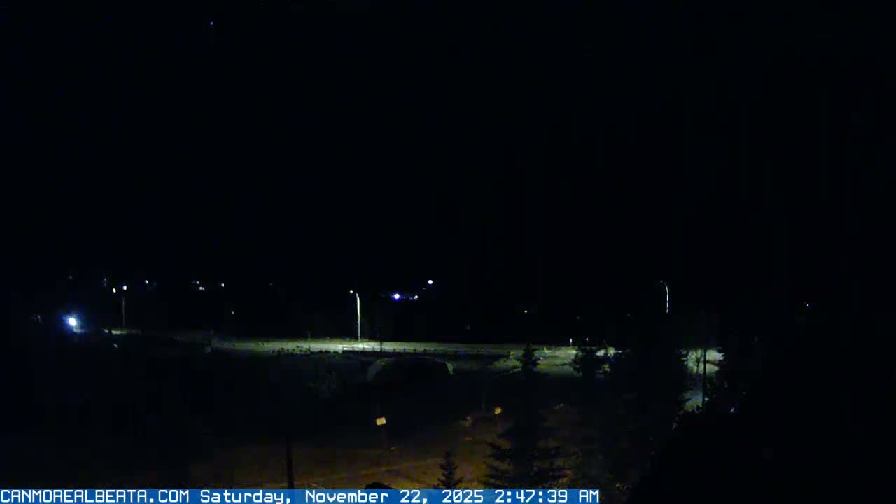 The image displays a dark outdoor night scene with scattered streetlights illuminating a road or bridge, all under clear skies.