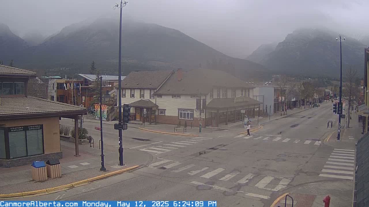 A mostly empty street scene in a mountain town on an overcast day, with low-lying clouds obscuring the peaks.
