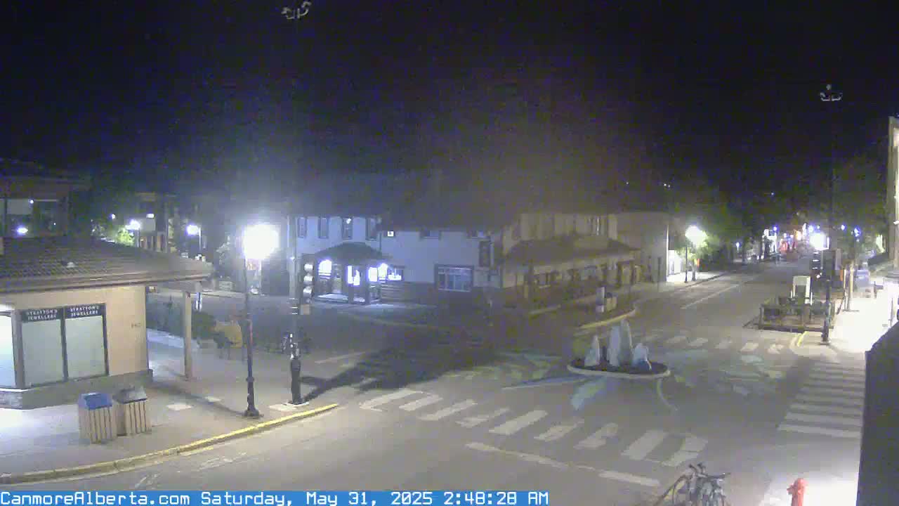 A nighttime view of a mostly empty street in a town, with several buildings visible under a clear sky.