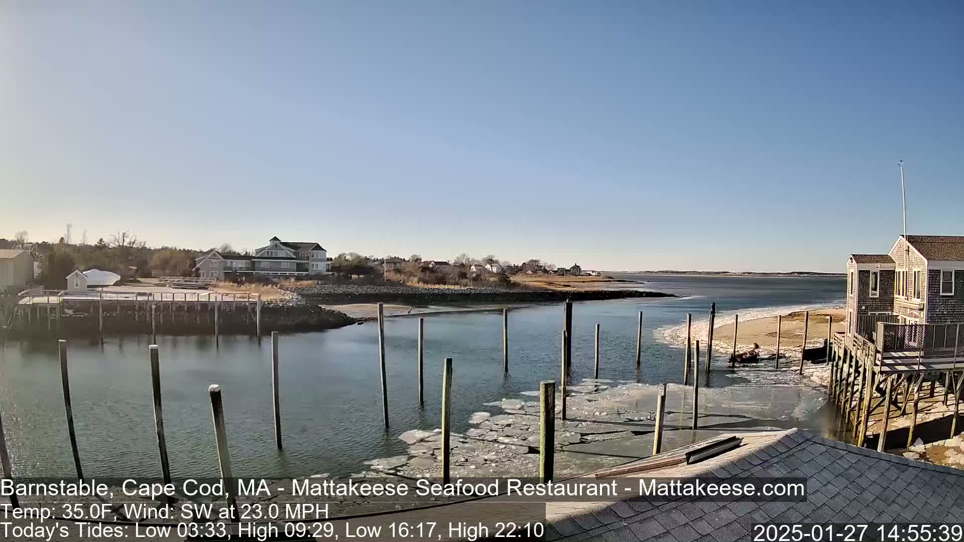 A waterfront scene with buildings, docks, and partially frozen water under a clear blue sky, and a southwest wind.