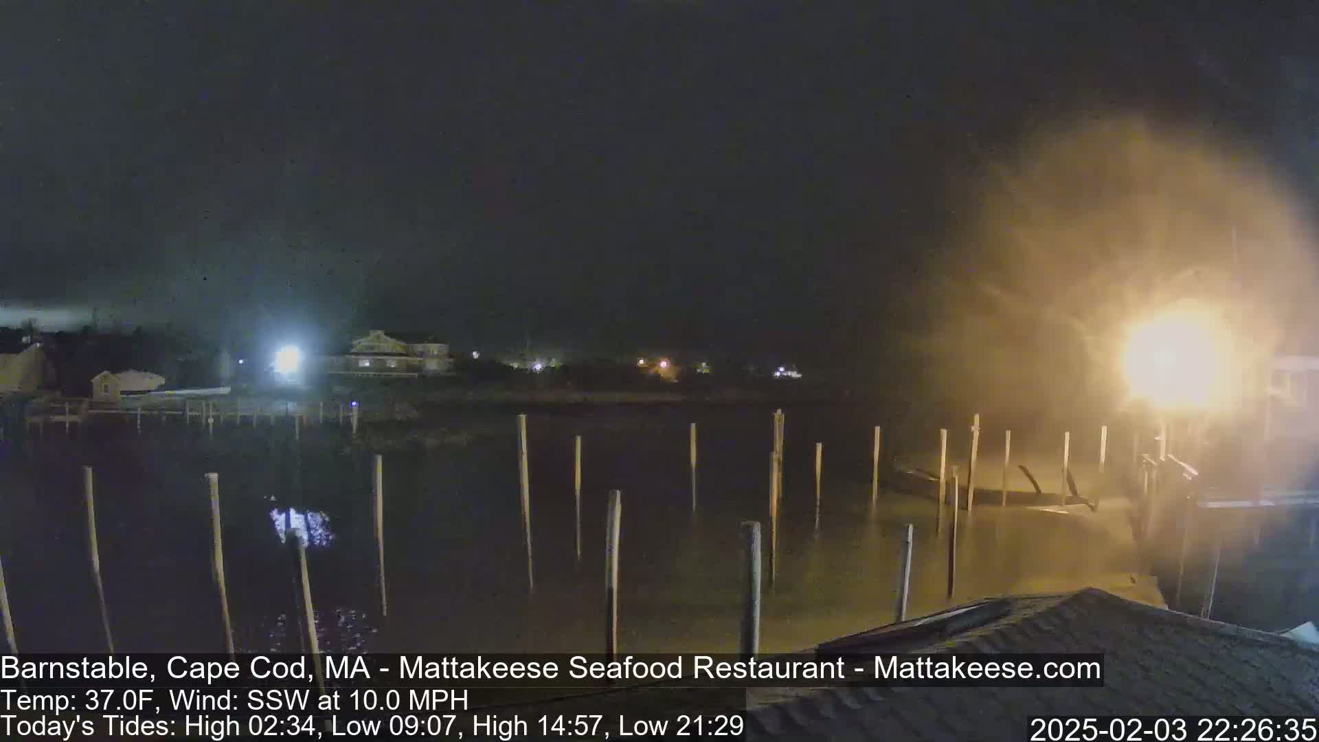 A nighttime view of a harbor with pilings in choppy water under a dark, windy sky.