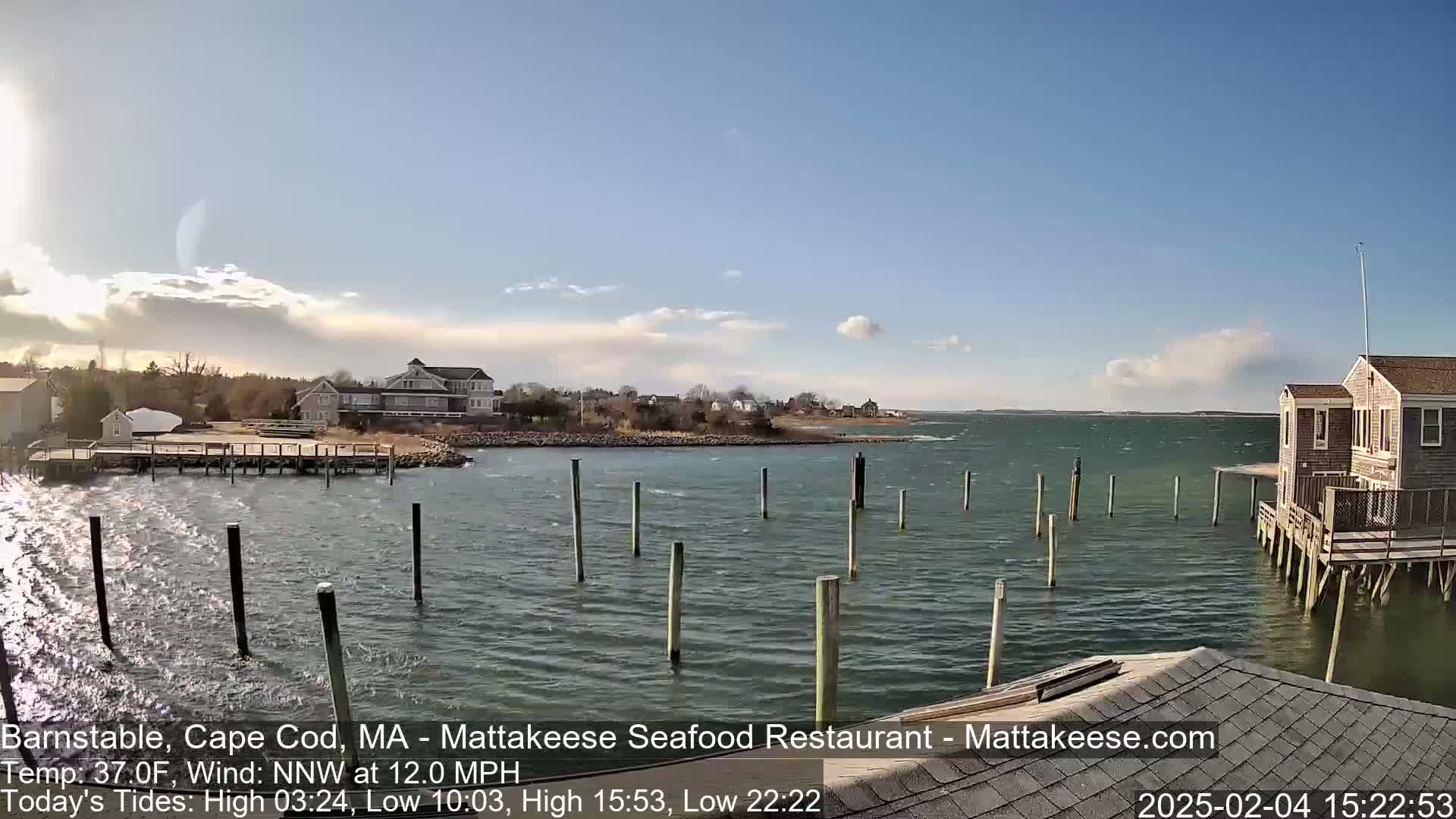 A partly cloudy day shows a calm bay with several docks and houses along the shore.