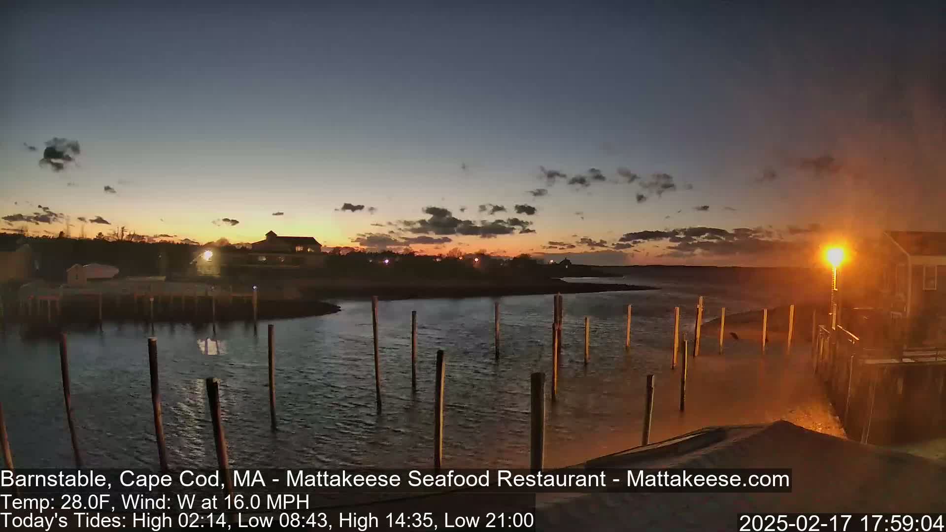 A twilight view of a calm body of water with several posts extending from a shoreline into the water, under a partly cloudy sky.