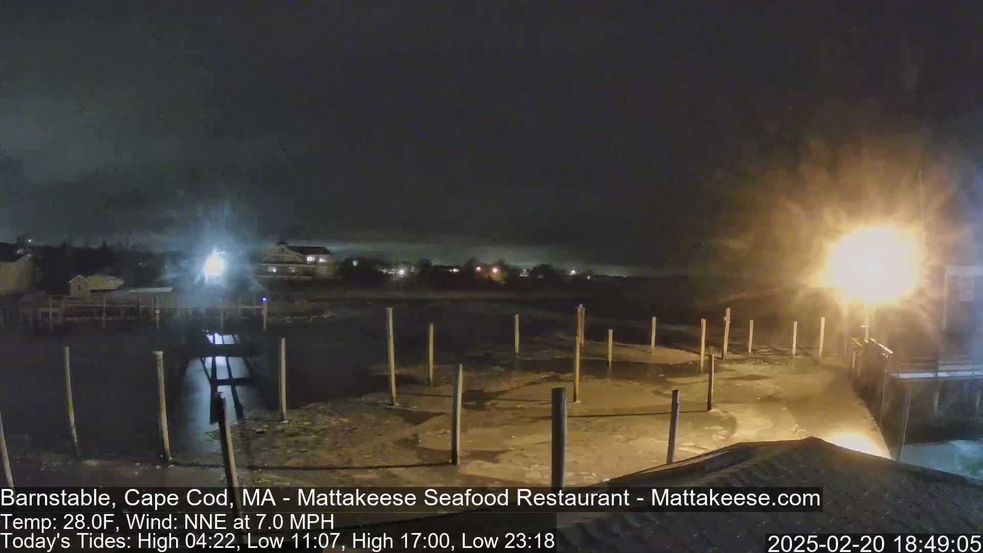 A nighttime view of a partially frozen dock with lights illuminating the scene under a dark, cloudy sky.