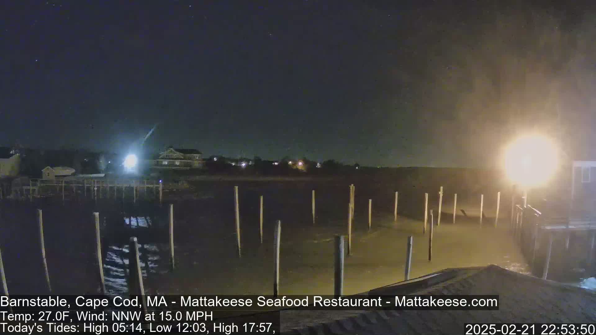 A nighttime view of a partially submerged dock under a dark, possibly stormy sky with a strong wind.