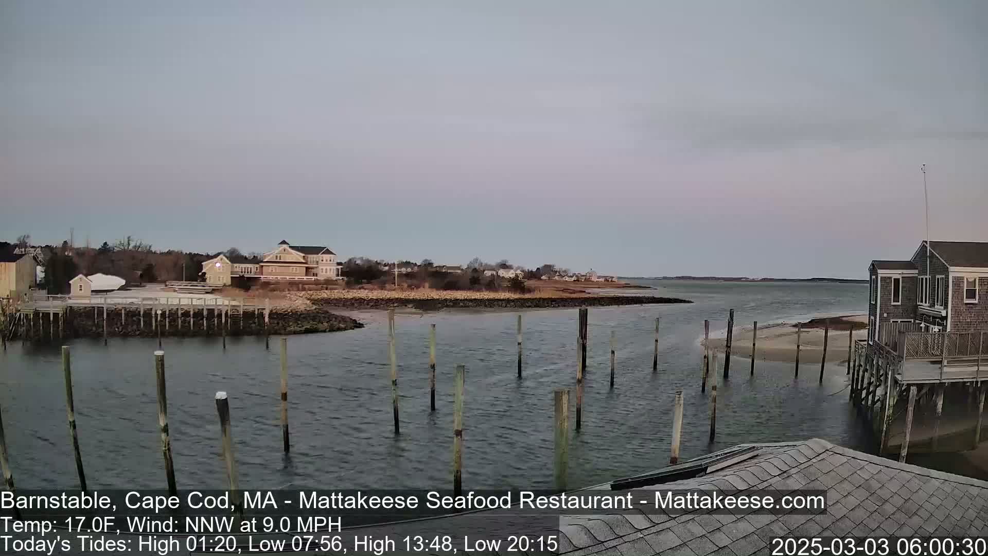 A calm body of water with wooden pilings and waterfront buildings under a twilight sky.