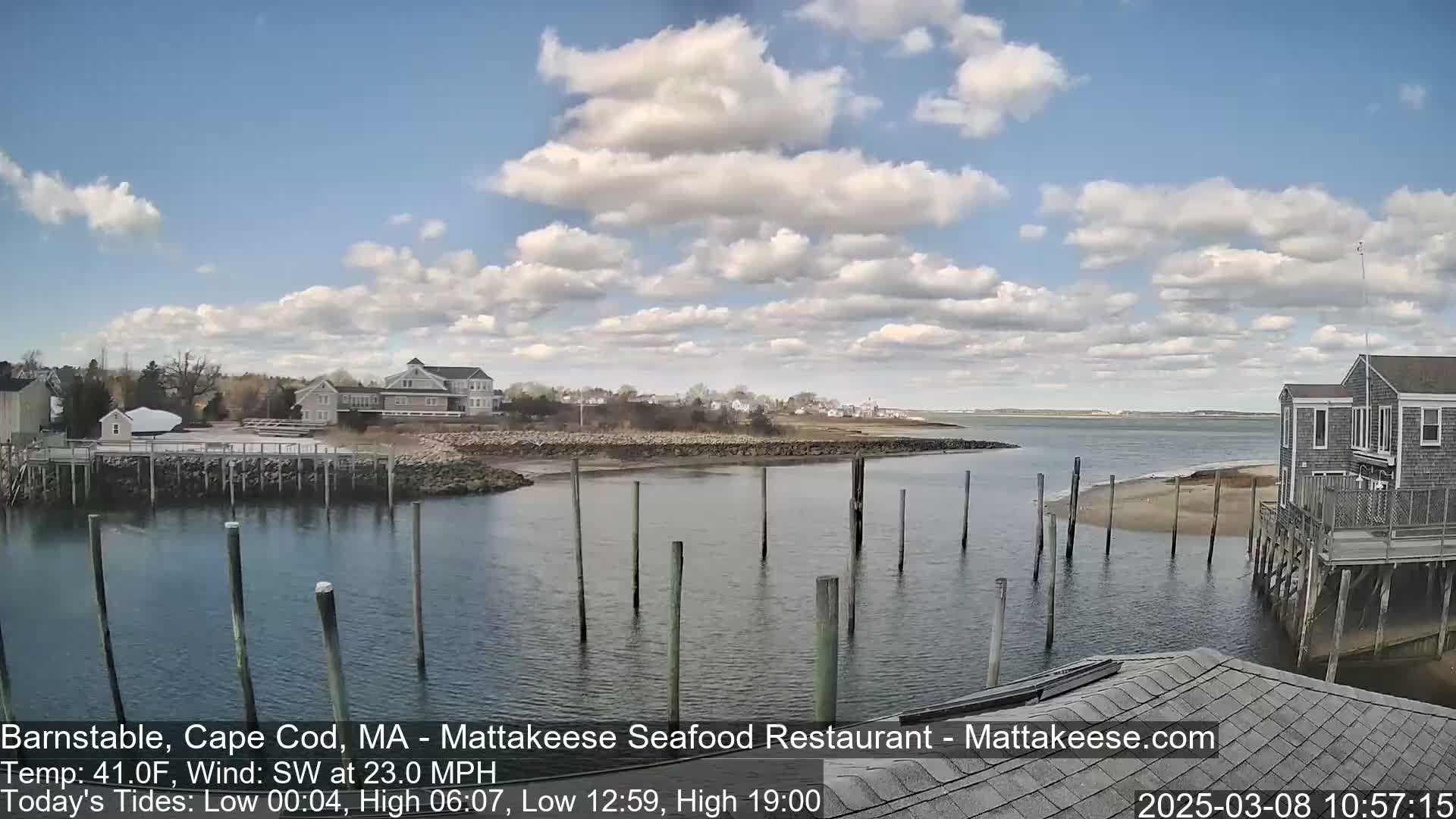 A partly cloudy day reveals a calm harbor scene with buildings and a small beach, under a southwest wind of 23 mph and a temperature of 41°F.