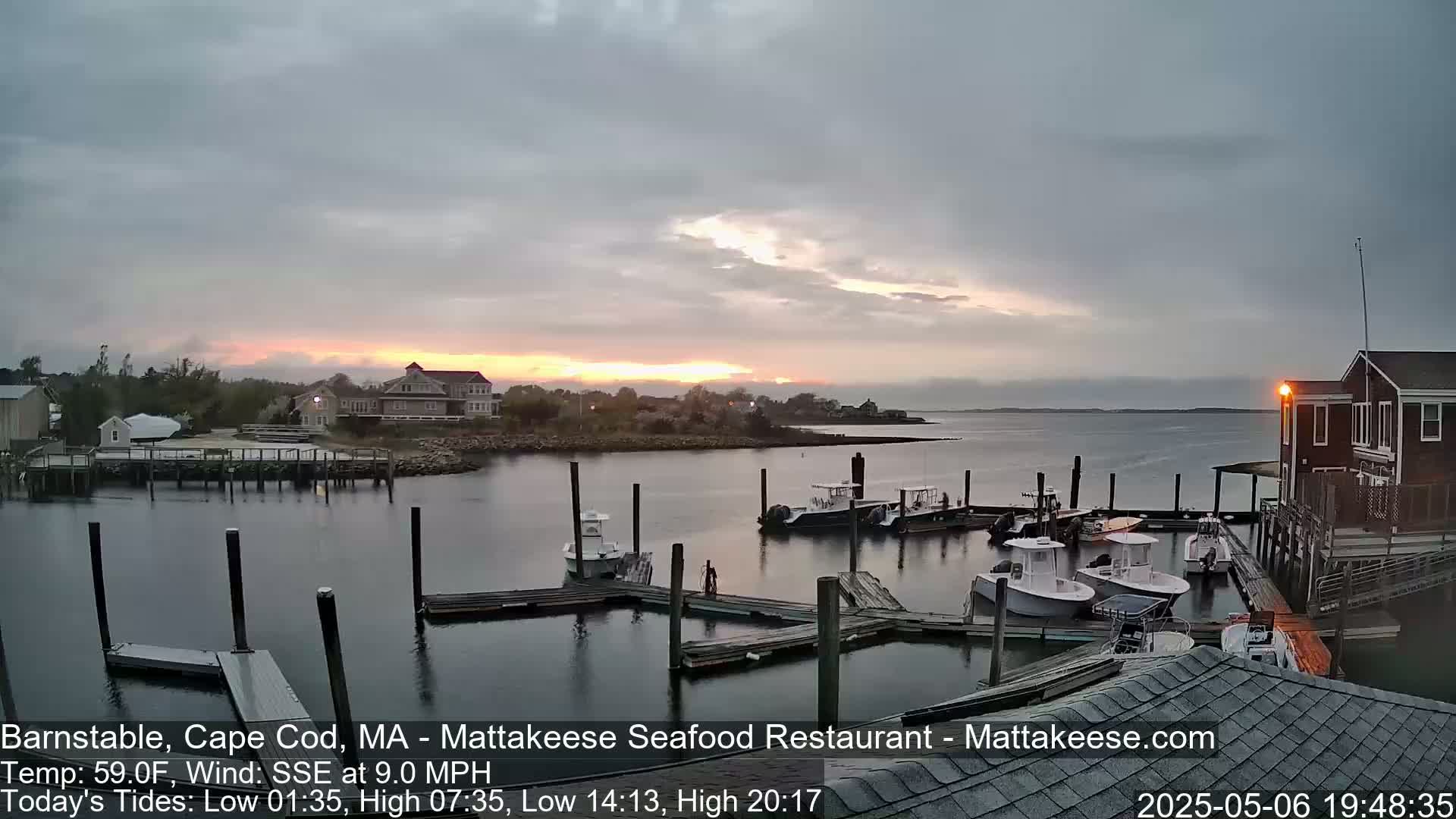 Several boats are docked at a marina at sunset under a mostly cloudy sky.