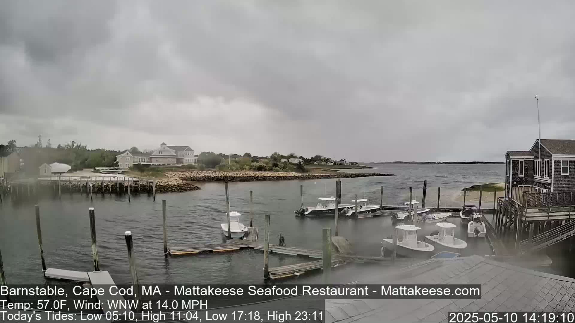 A small harbor with several boats docked at piers under an overcast sky, with a moderate wind.