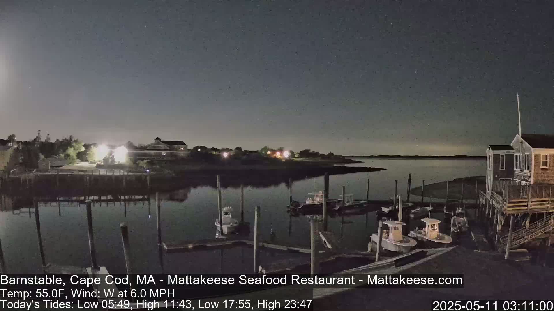 Several small boats are moored at a dock at night under a mostly clear sky.